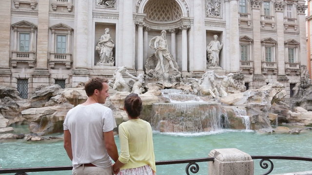 Rome couple taking picture photo with smartphone of Trevi Fountain, Italy. Happy young tourists couple traveling in Europe taking photos with smartphone camera. Man and woman happy.