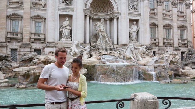 Romantic couple on travel taking selfie photo by Trevi Fountain in Rome, Italy. Happy young tourists couple traveling in Europe taking self-portrait with smartphone camera. Man and woman happy.