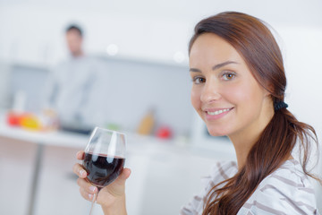 Lady holding glass of wine, partner in background