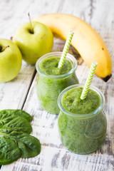 Green smoothie with apple,banana and spinach on a light backgrou