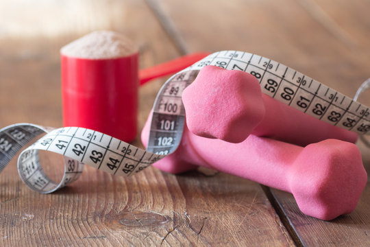 weight loss concept - with tape measure whey powder and pink dumbbells