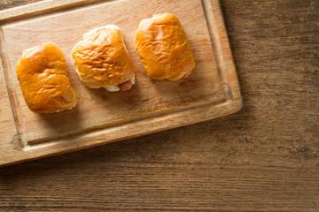 Bread with sausage on cutting board with wooden backgroud.