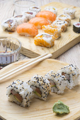 Different Sushi rolls,wasabi and ginger on a plate on wooden bac
