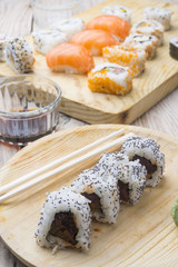 Different Sushi rolls,wasabi and ginger on a plate on wooden bac