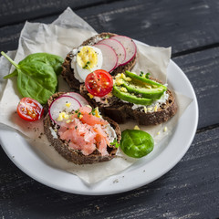 Assortment of sandwiches - sandwiches with cheese, radish,  quail egg, avocado and smoked salmon. Tasty breakfast, snack or appetizer with wine