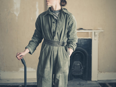 Woman with crowbar standing by fireplace