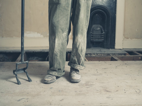 Feet and legs of person in boiler suit with crowbar