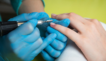 Obraz na płótnie Canvas Closeup shot of a woman in a nail salon receiving a manicure by a beautician with nail file. Woman getting nail manicure. Beautician file nails to a customer