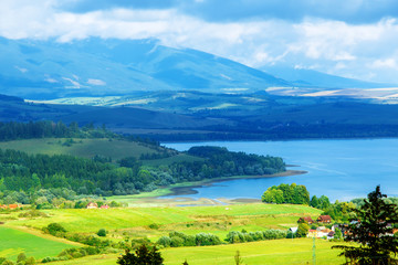Idyllic summer landscape with clear mountain lake  and green and yellow meadow. Central Europe.