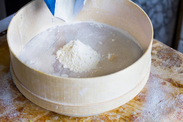 Flour is sifted through a wooden sieve 