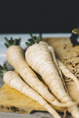 Parsley root with tomatoes on cutting board on a white background of the old wooden boards vintage close up