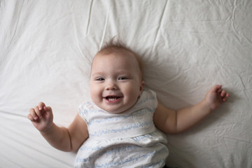 Toddler laugh baby on bed, first teeth © natalialeb