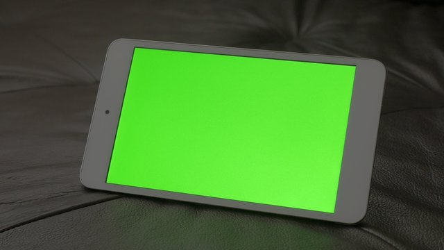 Green screen display presented on PC tablet computer 4K 2160p UltraHD footage - PC silver tablet on leather sofa 4K 3840X2160 UHD video 