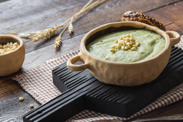 Broccoli cream soup with pine nuts and wholemeal bread, ears of corn, rustic