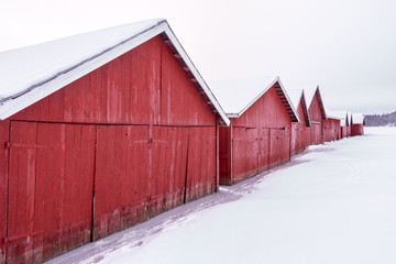Row of wooden red boathouses in winter