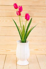 Red tulips in pot on wood texture background