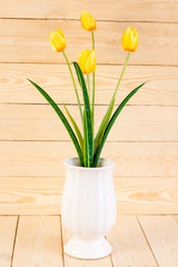 Yellow tulips in pot on wood texture background