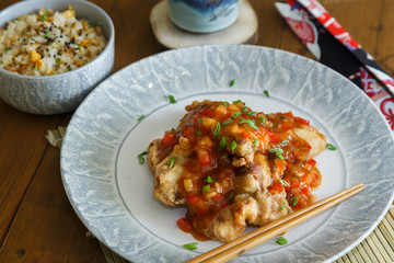 Sweet and sour pork and rice on plate with chopsticks, Chenese cuisine