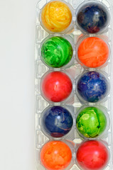 Bunte Eier / bunte Ostereier in einem Eierkarton, Plastik, Nahaufnahme, Makro, isoliert, weißer Hintergrund, Querformat, vertikal

