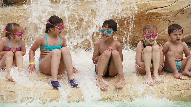 wet children sit on a rock near the water