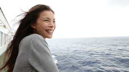 Cruise ship woman on boat in happy smiling looking looking away at sea. Young woman traveling on vacation travel sailing on open sea ocean. Young mixed race Asian Caucasian woman.
