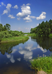 Landscape with river, forest, clouds and the reflection in the water.