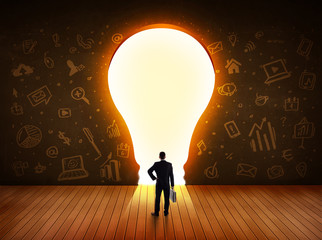 Obraz premium Business man looking at bright light bulb in the wall