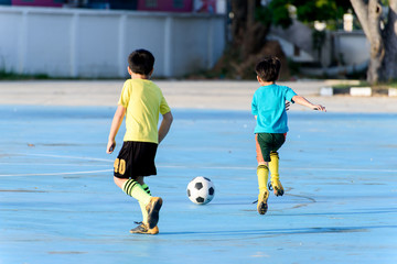 Boy play football on the blue concrete floor.