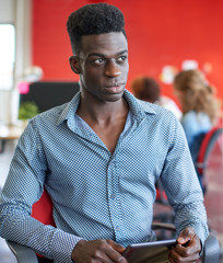 Confident male designer working on a digital tablet in red creative office space