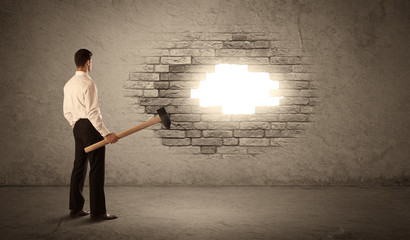 Business man hitting brick wall with hammer and opening a hole