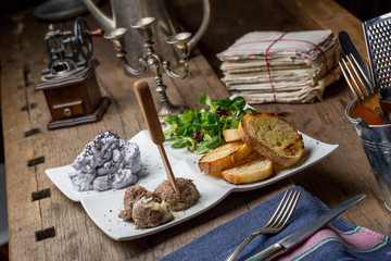 Tasty appetizers with chicken liver pate, valerian salad, toasted bread and blueberry mousse, on an old wooden table