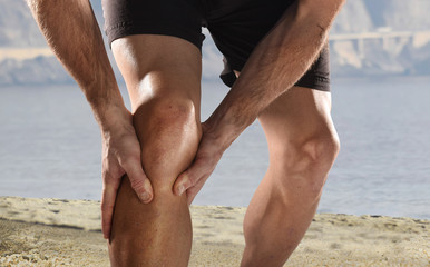 young sport man with athletic legs holding knee in pain suffering muscle injury running