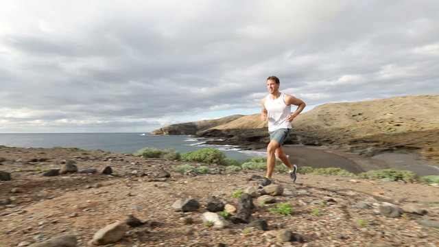 Sport runner trail running cross country. Fit male runner exercise training beautiful ocean nature landscape on Tenerife, Canary Islands, Spain.