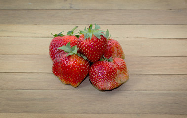 Strawberry berries in a basket on the wooden floor.