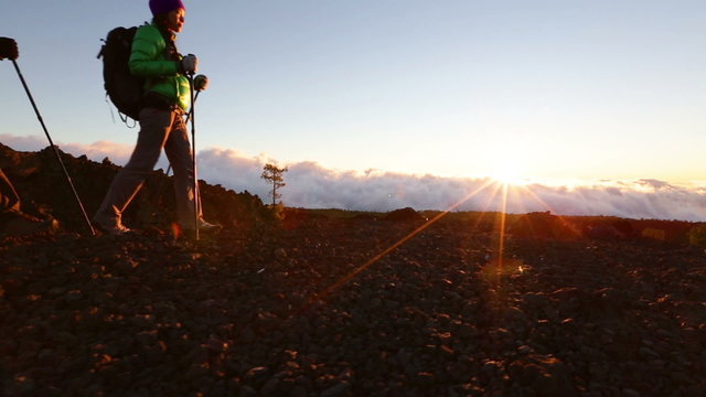 Hiking couple - hikers trekking at sunset. Hiker man and woman in beautiful mountain nature landscape. Woman and man hikers walking during hike on volcano Teide, Tenerife, Canary Islands, Spain.