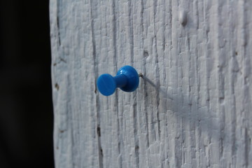 A paper needle is stuck in the wood and made a long shadow.