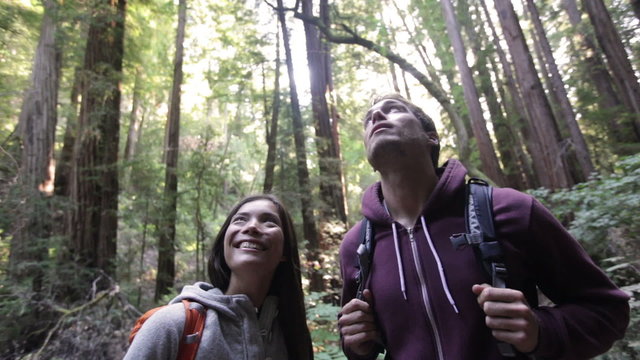 People in outdoor activity hiking in Redwoods forest, San Francisco. Couple. Hikers walking among Redwood trees near San Francisco, California, USA. Young happy Asian woman and Caucasian man.