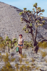 Fototapeta premium woman traveler walking with suitcase in desert