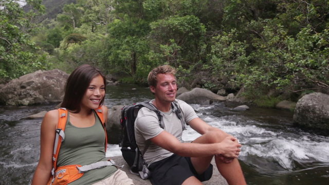 Hiking people in outdoor activity wearing backpacks relaxing. Hikers, woman and man hiker looking with smiling happy. Healthy lifestyle image from Iao Valley State Park, Wailuku, Maui, Hawaii, USA.