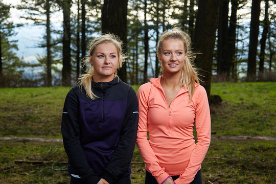 Running Women Standing Side by Side in Forest Looking away from