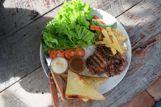 Grilled steak, French fries, bread and vegetables set
