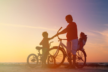 Obraz na płótnie Canvas silhouette of father with two kids on bikes