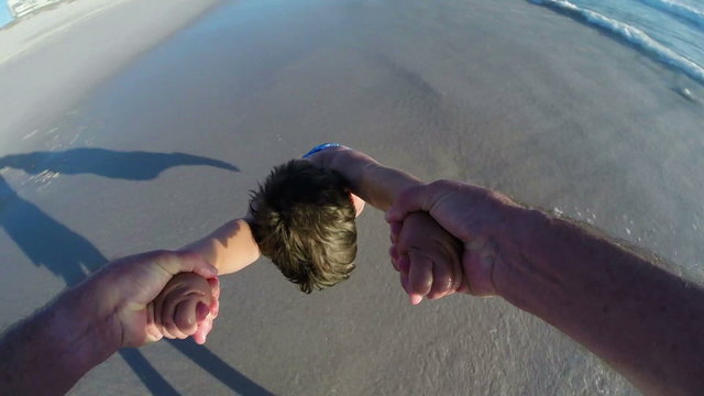 Slow motion POV of Father swinging happy child around in circles on beach,Cape Town, South Africa