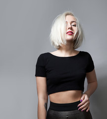 Fashion woman with red lipstick and short hair and wearing a  black T-shirt, standing on the gray...