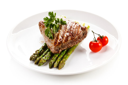 Grilled beefsteak and asparagus on white background 