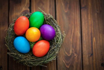 colorful Easter eggs in the nest on the old wooden background