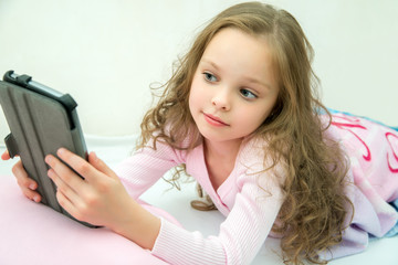 happy little girl lying on bed with tablet computer © jutaphoto