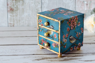 A handmade mini chest of three drawers decoupaged with blue floral vintage paper and gold leaf - obrazy, fototapety, plakaty