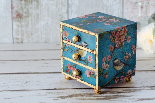 A handmade mini chest of three drawers decoupaged with blue floral vintage paper and gold leaf