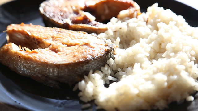 rice fish black plate wooden table shifts the focus